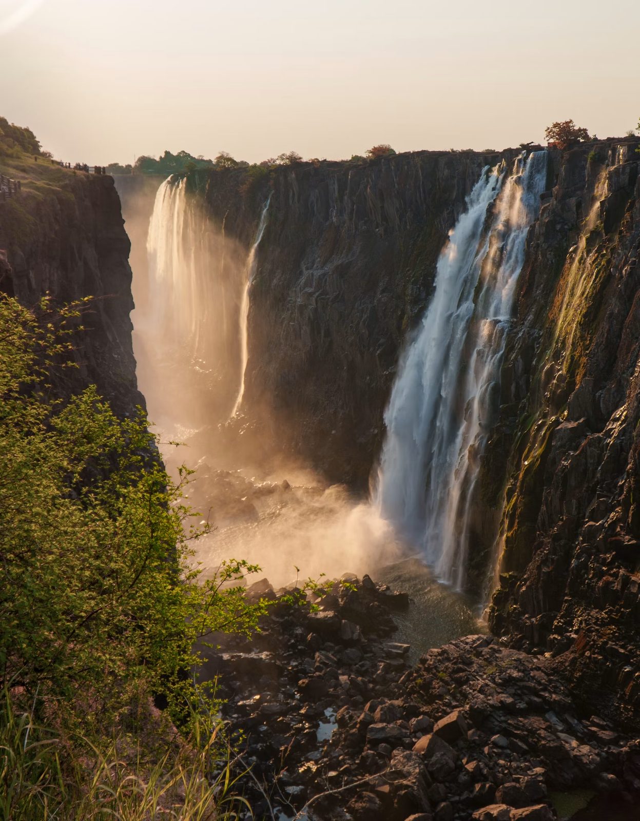 Powerful Victoria Falls cascading down rocky cliffs at sunset, Zimbabwe